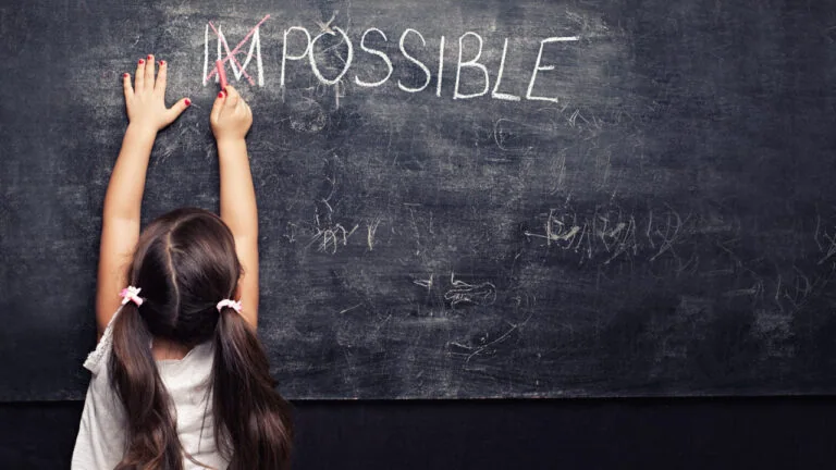 Child reaching up on a chalkboard